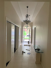 Freshly painted hallway with white walls, ceiling and cornices leading to an arched front entry